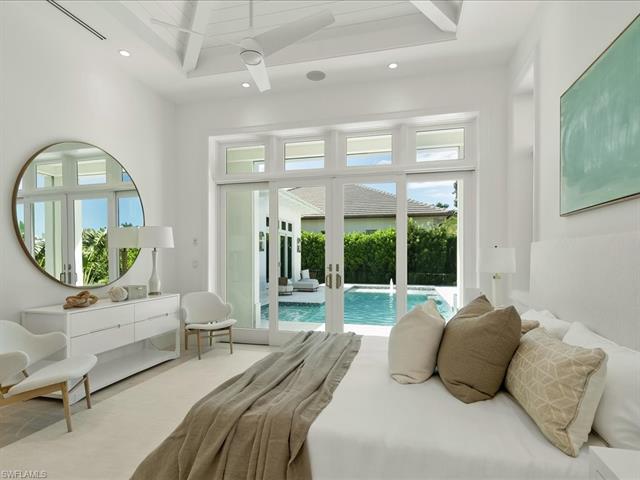 Bedroom featuring a towering ceiling, french doors, access to outside, and multiple windows
