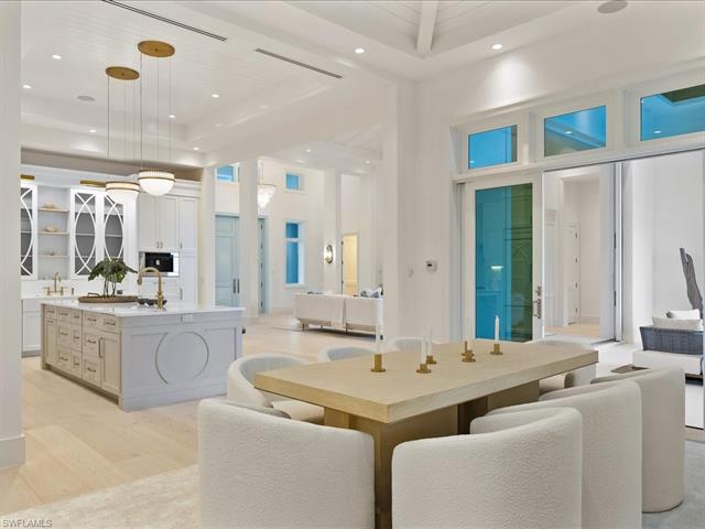 Dining room featuring sink, a towering ceiling, and light hardwood / wood-style floors