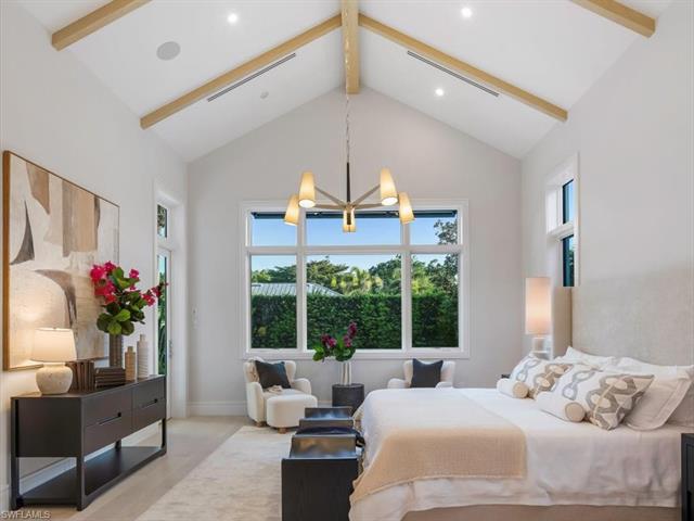 Bedroom with high vaulted ceiling, baseboards, beamed ceiling, visible vents, and a notable chandelier