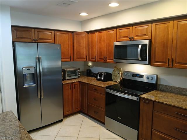 Kitchen featuring dark stone counters, stainless steel appliances, and light tile flooring