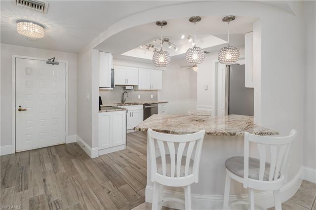 Kitchen with kitchen peninsula, stainless steel appliances, hanging light fixtures, and white cabinets