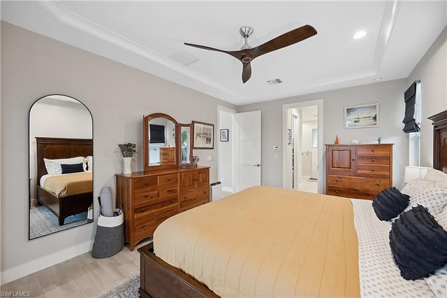 Bedroom featuring a raised ceiling, ceiling fan, hardwood / wood-style floors, and connected bathroom