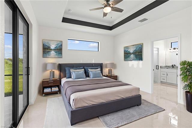 Tiled bedroom featuring connected bathroom, access to outside, ceiling fan, a raised ceiling, and ornamental molding