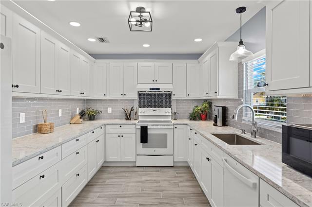 Kitchen with white cabinetry, backsplash, white appliances, and sink