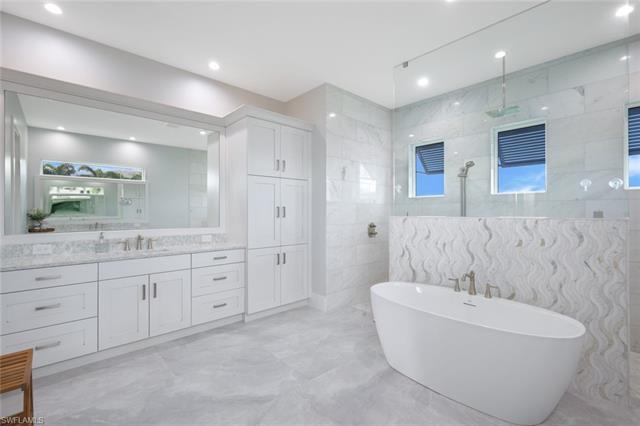 Bathroom with tile walls, tile patterned floors, vanity, and plenty of natural light