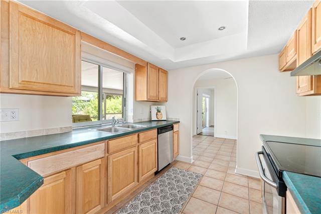Kitchen featuring appliances with stainless steel finishes, a tray ceiling, a healthy amount of sunlight, and light tile patterned floors