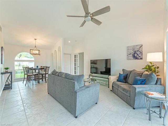 Living room featuring ceiling fan with notable chandelier and light tile patterned floors