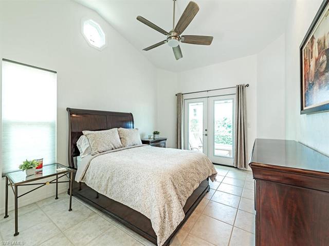 Tiled bedroom featuring ceiling fan, access to exterior, high vaulted ceiling, and french doors