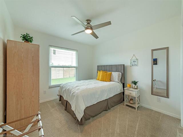 Bedroom with ceiling fan and light carpet