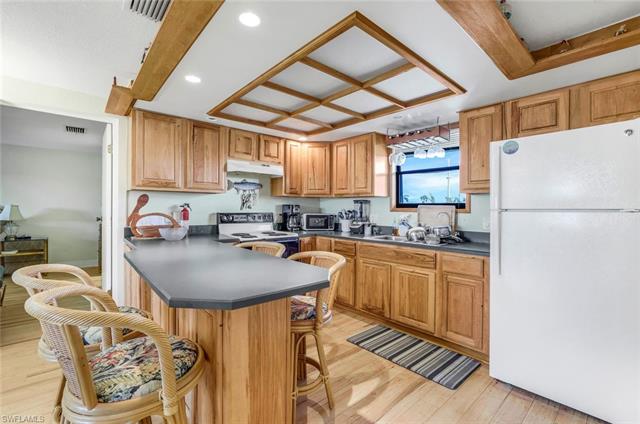 Kitchen featuring kitchen peninsula, a breakfast bar area, light hardwood / wood-style floors, and white appliances