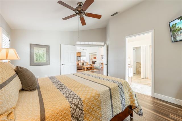 Bedroom with ceiling fan, lofted ceiling, wood-type flooring, and ensuite bath