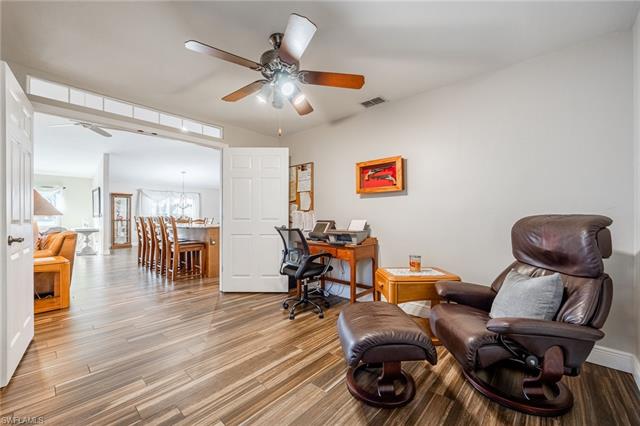 Office space with hardwood / wood-style floors and ceiling fan with notable chandelier