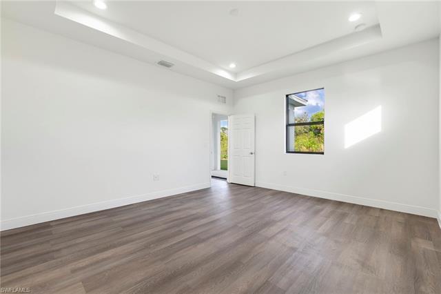 Empty room featuring dark hardwood / wood-style flooring and a tray ceiling