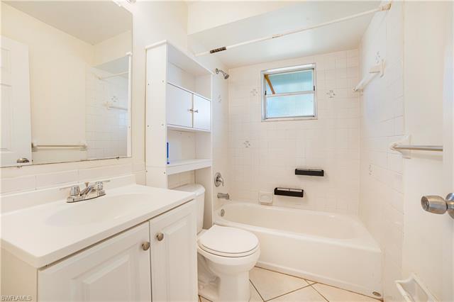 Full bathroom with vanity, tile patterned floors, toilet, and tiled shower / bath
