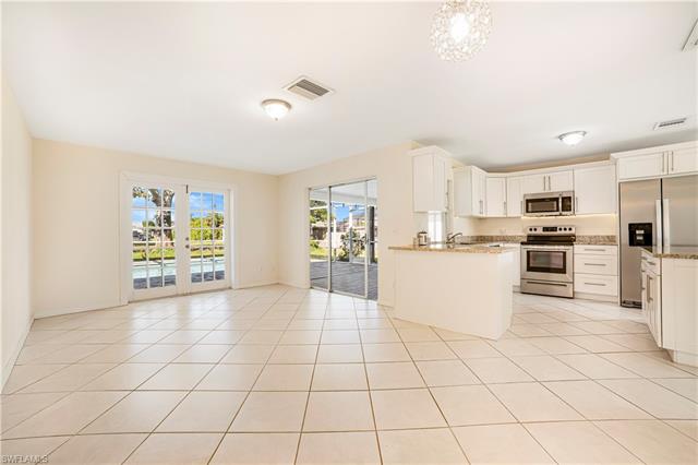 Kitchen with light stone countertops, appliances with stainless steel finishes, light tile patterned flooring, and white cabinets
