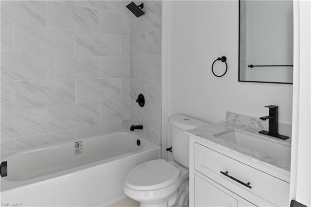 Full bathroom featuring toilet, vanity, and tiled shower / bath