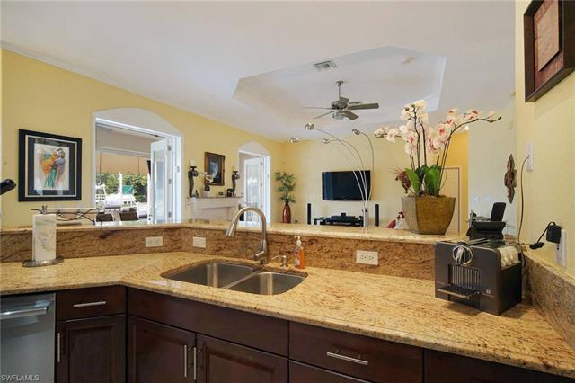 Kitchen with sink, ceiling fan, dishwasher, light stone counters, and dark brown cabinetry