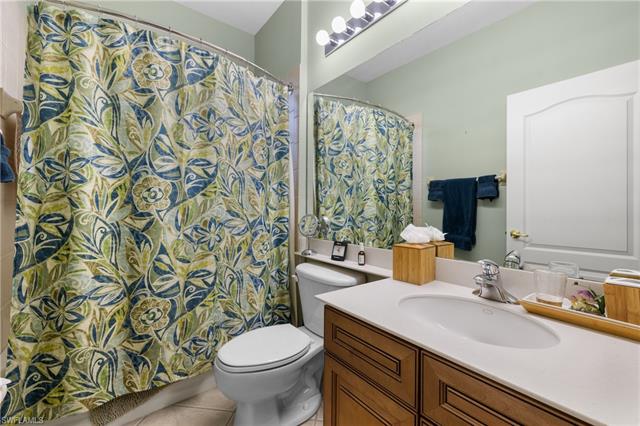 guest Bathroom featuring tile patterned flooring, vanity, toilet, and a shower with shower curtain