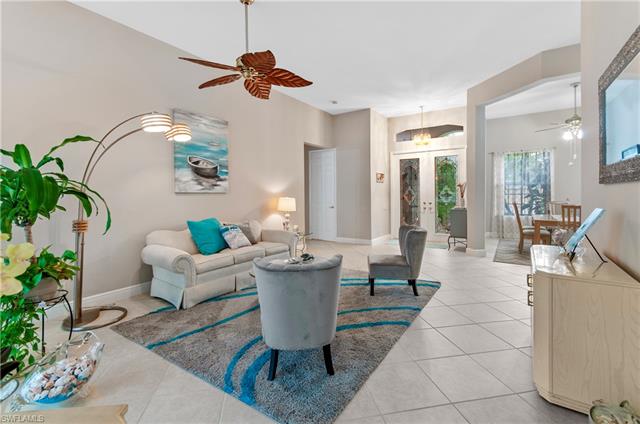 Living room with light tile patterned floors, french doors, and ceiling fan
