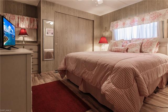 Bedroom featuring ceiling fan, laminate / wood-style floors, and wooden walls