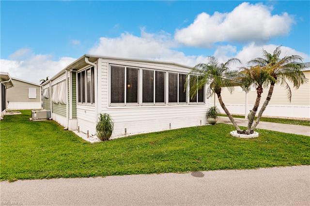 View of property exterior with a yard and palm tree