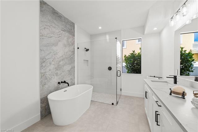 Bathroom with double vanity, recessed lighting, a soaking tub, a stall shower, and a sink