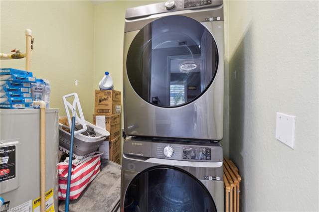 Laundry area featuring water heater and stacked washer / drying machine