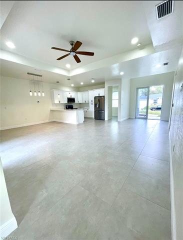 Unfurnished living room with ceiling fan and a raised ceiling