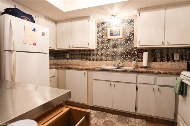 Kitchen with backsplash, sink, white cabinets, and white appliances