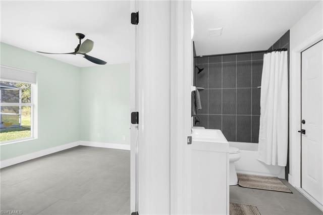 Full bathroom with ceiling fan, toilet, shower / bath combo with shower curtain, and sink