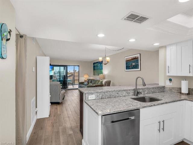 Kitchen with white cabinetry, dishwasher, sink, kitchen peninsula, and a chandelier