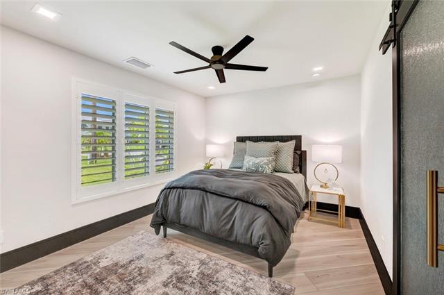 Bedroom featuring a barn door, ceiling fan, and light hardwood / wood-style floors