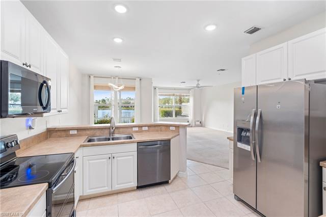 Kitchen with white cabinets, stainless steel fridge with ice dispenser, and light carpet