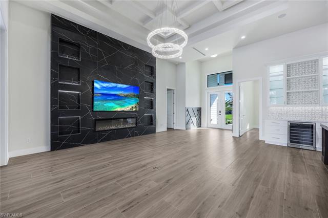 Unfurnished living room featuring wine cooler, beam ceiling, hardwood / wood-style flooring, a notable chandelier, and coffered ceiling