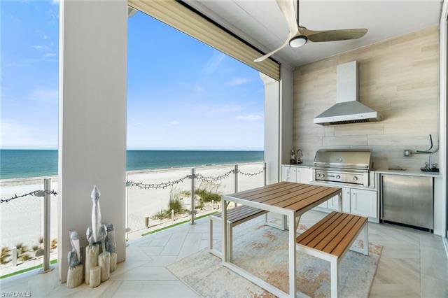 Balcony featuring a water view, an outdoor kitchen, and a view of the beach