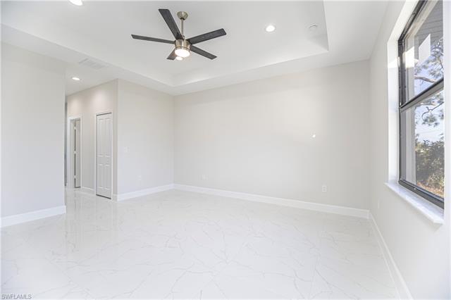 Tiled spare room featuring ceiling fan and a raised ceiling