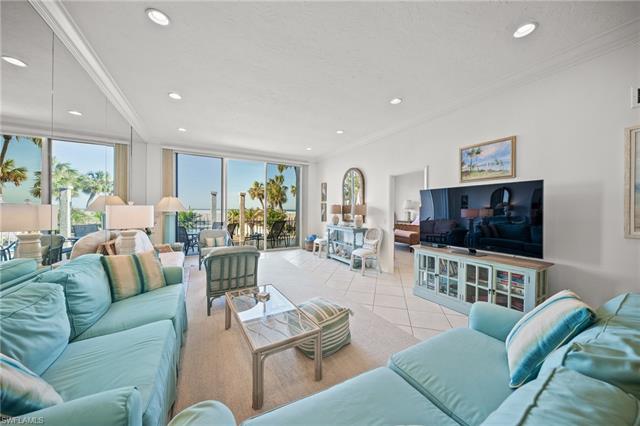 Living room with crown molding, a textured ceiling, and light tile patterned floors. Expansive mirrored walls, volume ceilings and a grand view of the beach.