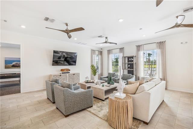 Living room featuring ornamental molding, light tile patterned floors, and ceiling fan