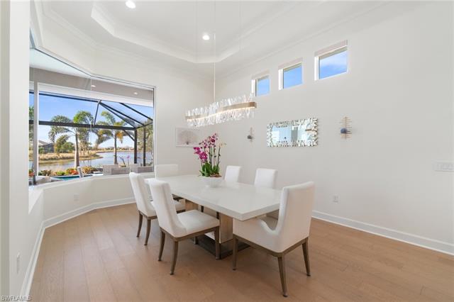 Dining space with light hardwood / wood-style flooring, ornamental molding, a raised ceiling, and a water view