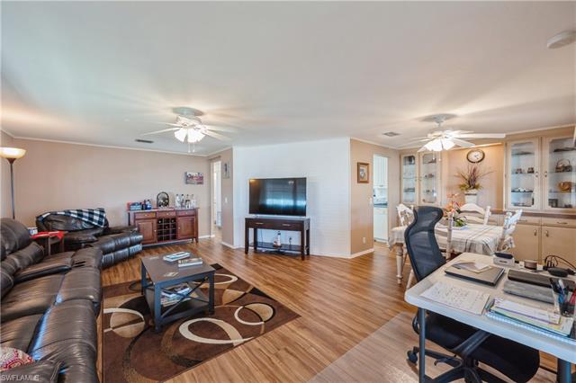 Living area featuring baseboards, light wood finished floors, a ceiling fan, and crown molding