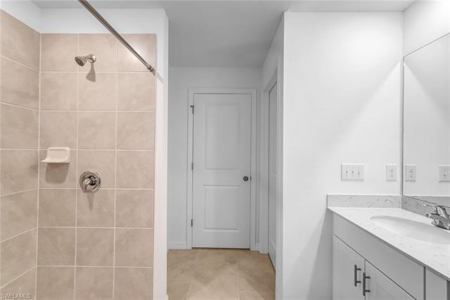 Bathroom with tile patterned flooring, a tile shower, and vanity