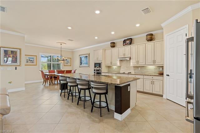 Kitchen with decorative backsplash, light stone counters, ornamental molding, under cabinet range hood, and a sink