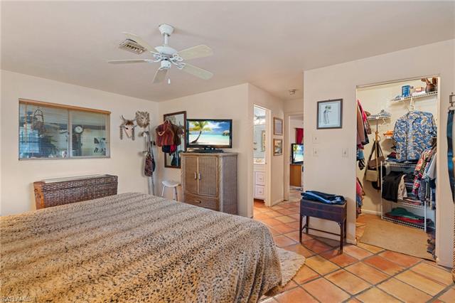 Bedroom with light tile patterned floors, visible vents, a ceiling fan, a walk in closet, and a closet