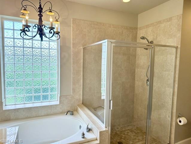 Bathroom featuring plenty of natural light, an inviting chandelier, and shower with separate bathtub