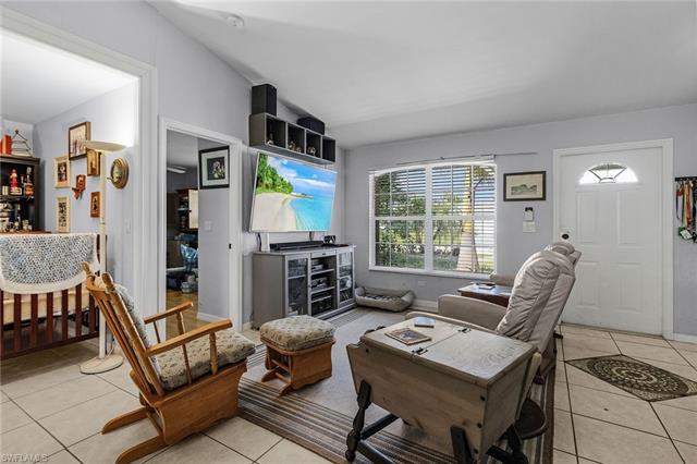 Living room with lofted ceiling, light tile patterned floors, and baseboards
