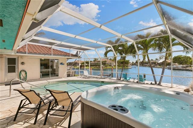 Outdoor pool with a patio, a water view, a lanai, and a hot tub