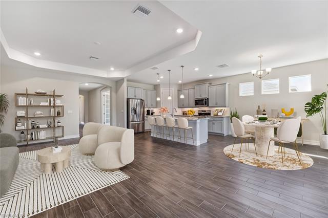 Living room featuring wood tiled floor, visible vents, a raised ceiling, and recessed lighting