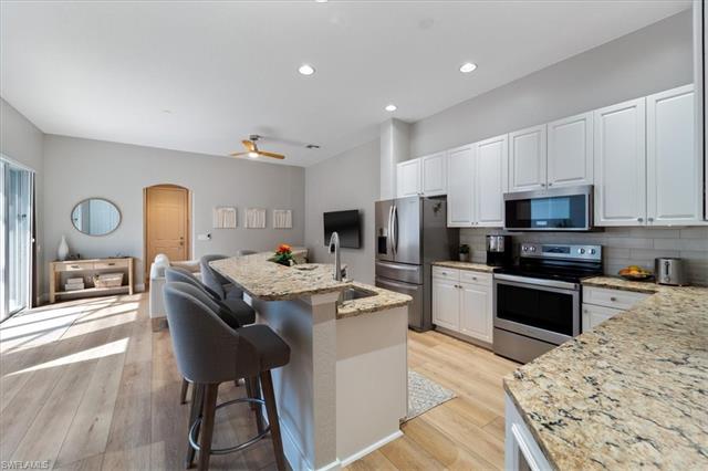 Kitchen with appliances with stainless steel finishes, arched walkways, light wood-style floors, and a sink