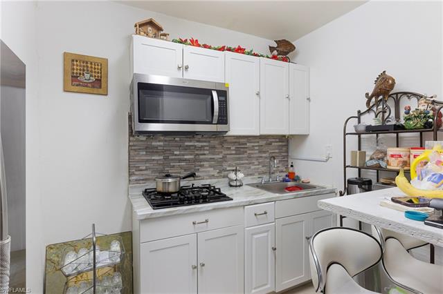 Kitchen featuring tasteful backsplash, stainless steel microwave, white cabinets, and a sink