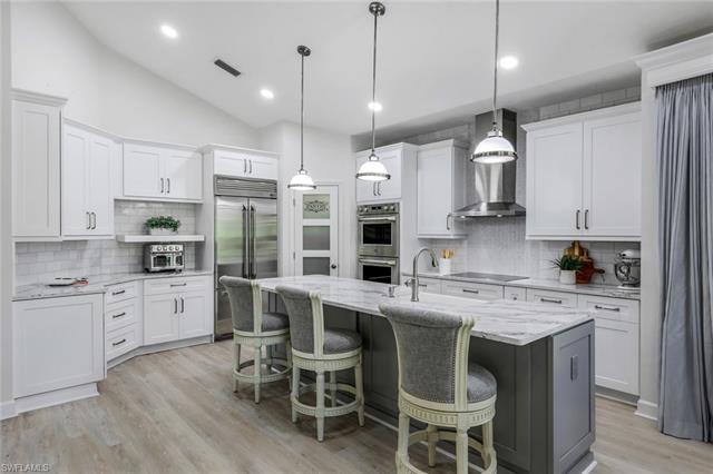 Kitchen with appliances with stainless steel finishes, a center island with sink, visible vents, and white cabinetry